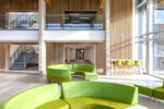 NIAB building Cambridge, entrance interior showing tall ceiling heights, panelled walls and lime green circular lounge sofas.