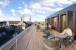 Computer Generated Image of roof terrace with customers socialising, working and reading, with a view over central oxford