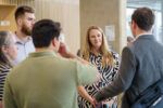 A group of five people chatting and smiling in the bright open foyer of the NIAB building, Cambridge.