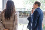 Three guests having a discussion around an A1 display board on an aisle featuring building information on Journey Campus. They are in the foyer of the NIAB building, Cambridge.