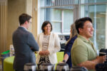 People talking and smiling in a bright open reception spaces during an event at the NIAB building in Cambridge, UK.